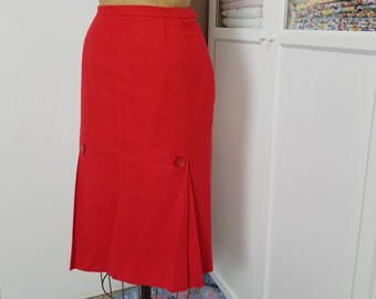 May include: A red skirt with a pleated hem and two buttons on the back. The skirt is on a dress form.