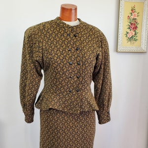 May include: A brown and black geometric patterned skirt suit with a fitted jacket and a skirt that falls to the knee.