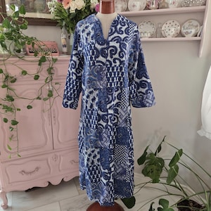 Peut inclure: Une robe longue à manches longues, arrivant au mollet, présentant un motif patchwork bleu et blanc avec divers designs géométriques, floraux et cachemire complexes. Le vêtement possède un col en V, une coupe droite et une texture matelassée.