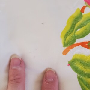 Puede incluir: Tela blanca con peque&ntilde;os agujeros y un dise&ntilde;o floral verde y amarillo.