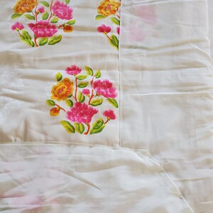 Puede incluir: Tela blanca con un patr&oacute;n floral. Las flores son rosas, amarillas y verdes. La tela es lisa y tiene un brillo sutil.