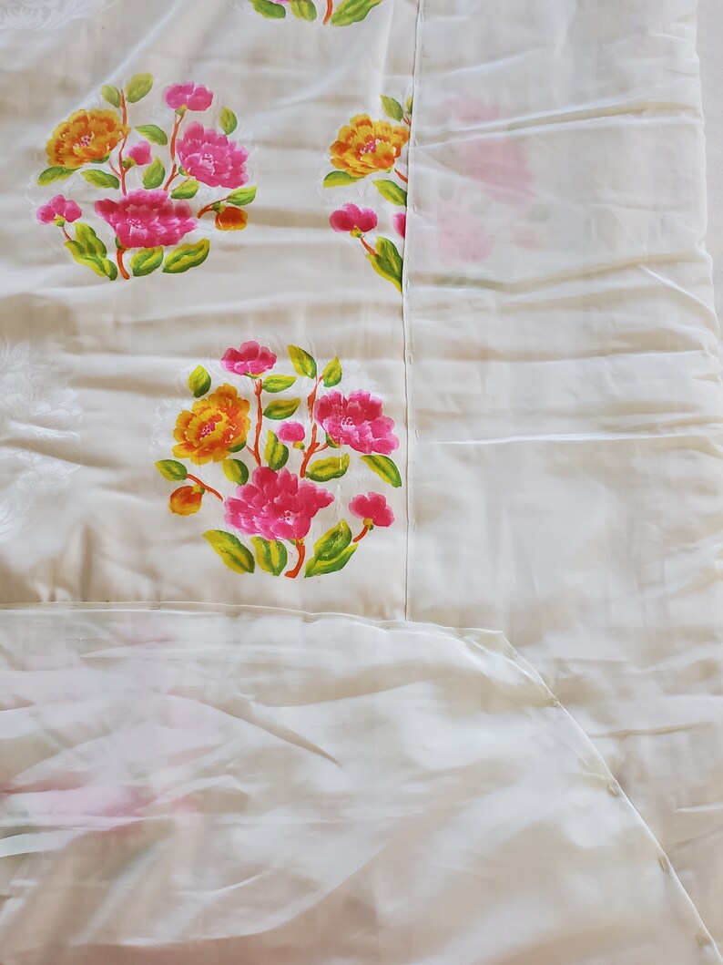 Puede incluir: Tela blanca con un patr&oacute;n floral. Las flores son rosas, amarillas y verdes. La tela es lisa y tiene un brillo sutil.