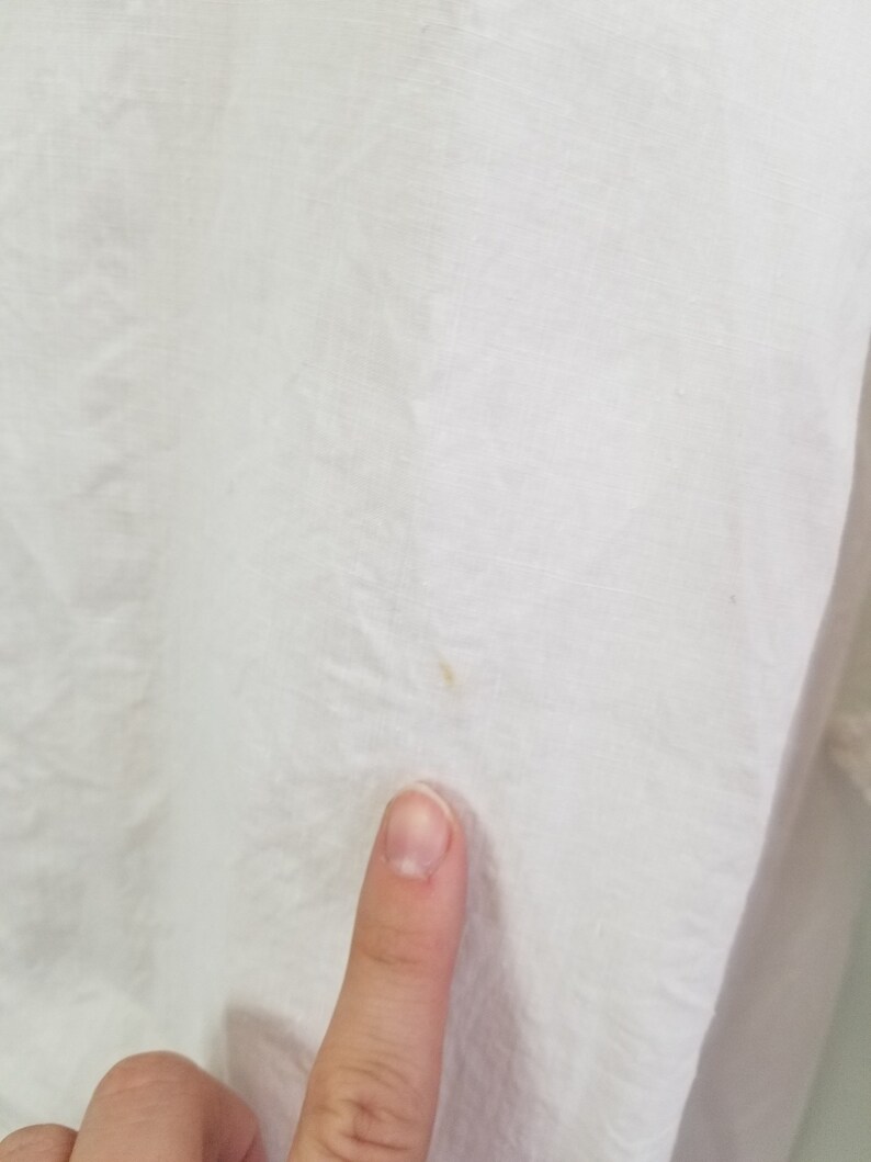 May include: Close-up of a white fabric surface with a small yellow stain.