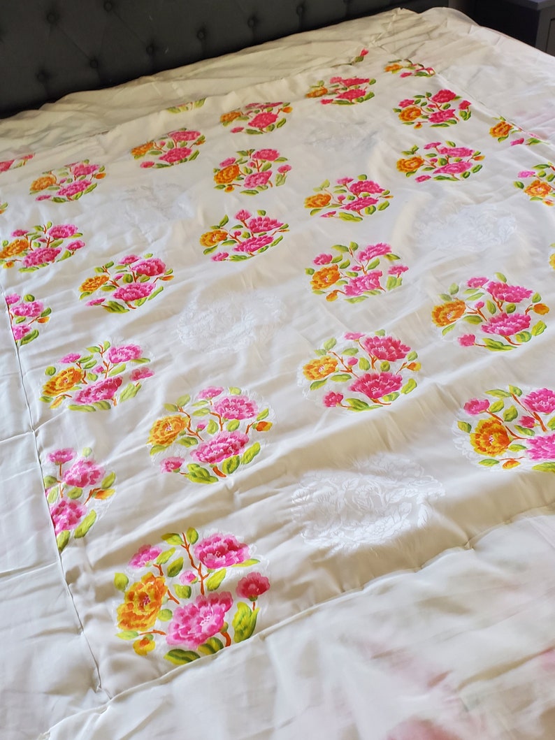 Puede incluir: Un edred&oacute;n blanco con un patr&oacute;n floral. Las flores son rosas, amarillas y verdes. El edred&oacute;n est&aacute; hecho de una tela suave y c&oacute;moda.