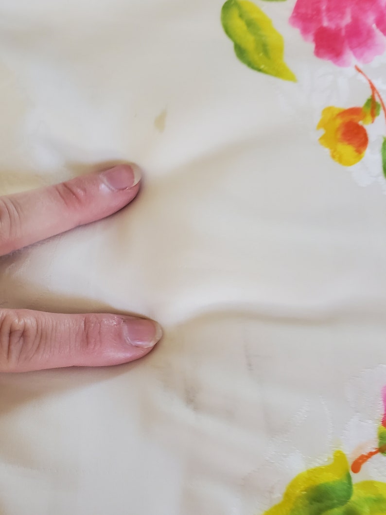 Puede incluir: Primer plano de una tela blanca con estampado floral. La tela tiene algunas manchas de color marr&oacute;n claro.