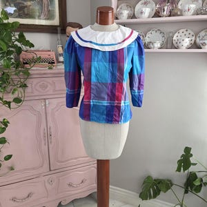 Bluzka w kratę Madras w stylu lat 70. i 80. w chłodnym odcieniu, zapinana na guziki z tyłu i z dużym kołnierzem, rozmiar średni do dużego