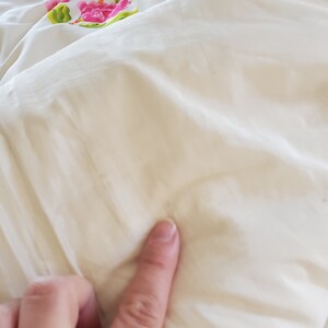 Puede incluir: Primer plano de un edred&oacute;n blanco con un patr&oacute;n floral. El edred&oacute;n est&aacute; hecho de una tela suave y lisa y tiene un brillo sutil.