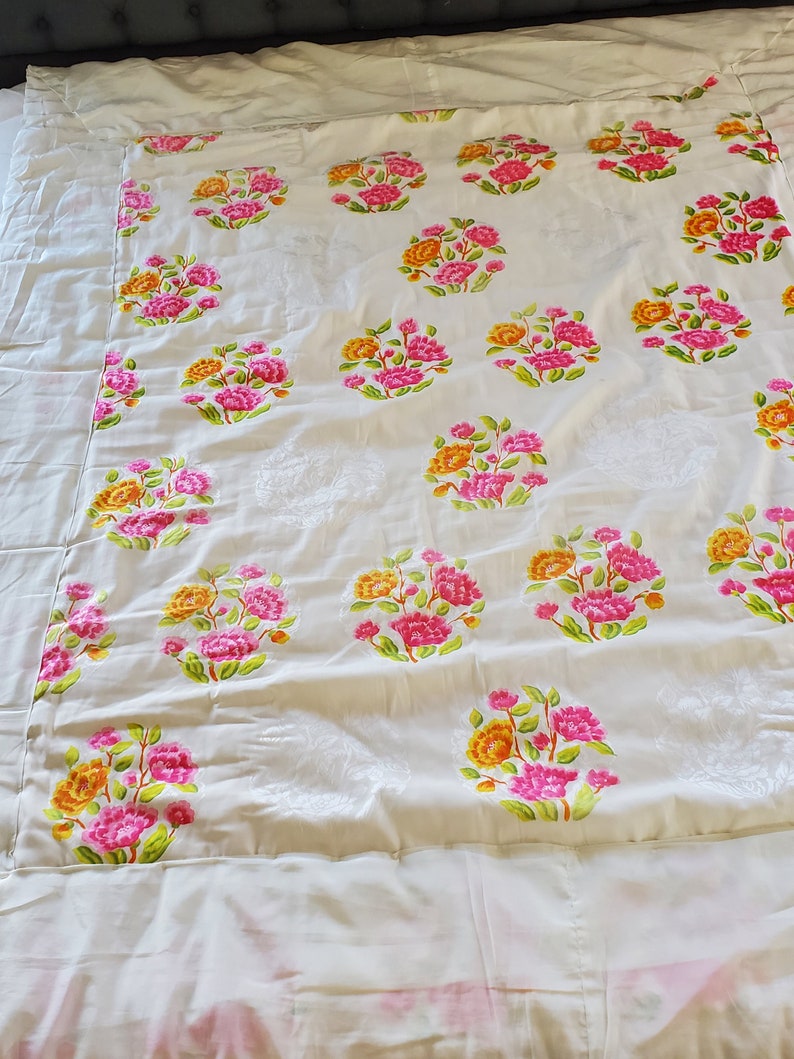 Puede incluir: Bedding blanco con un patr&oacute;n floral. Las flores son rosas, amarillas y verdes. La ropa de cama tiene un borde blanco.