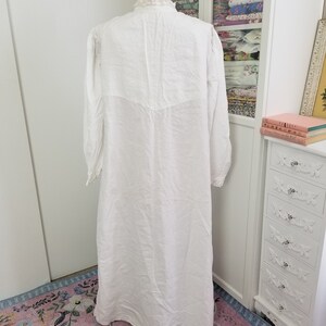May include: A white cotton nightgown with a lace trim around the neckline and cuffs. The nightgown is long and flowing, and it is displayed on a mannequin.