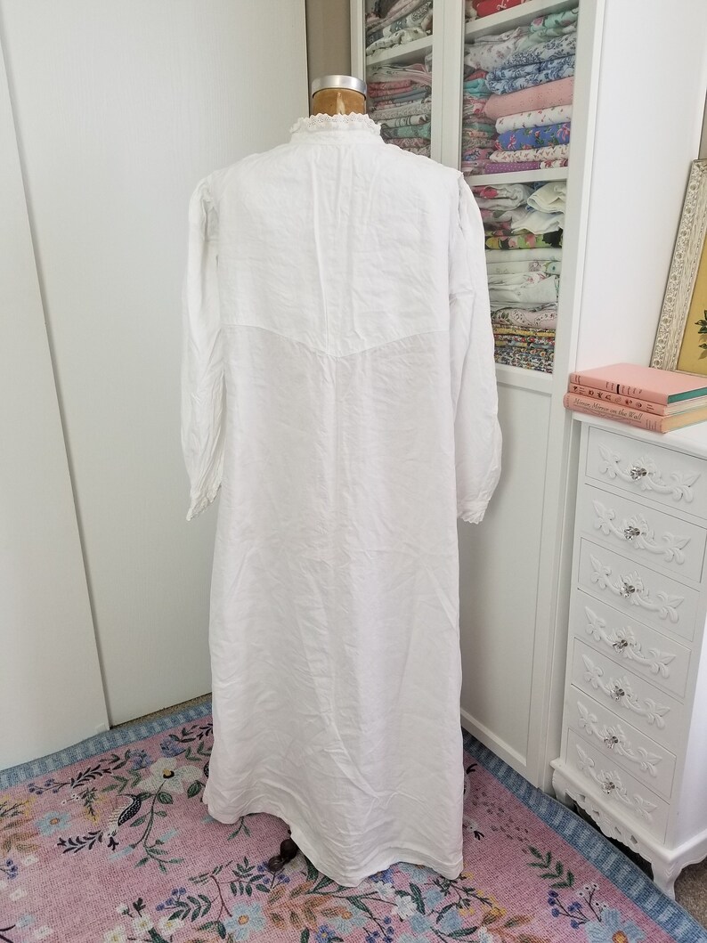 May include: A white cotton nightgown with a lace trim around the neckline and cuffs. The nightgown is long and flowing, and it is displayed on a mannequin.