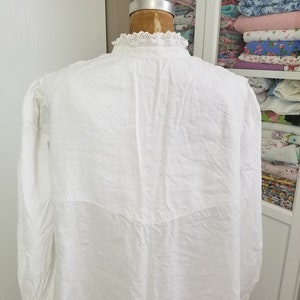 May include: White long-sleeved shirt with a lace collar. The shirt is made from a lightweight fabric and has a relaxed fit.