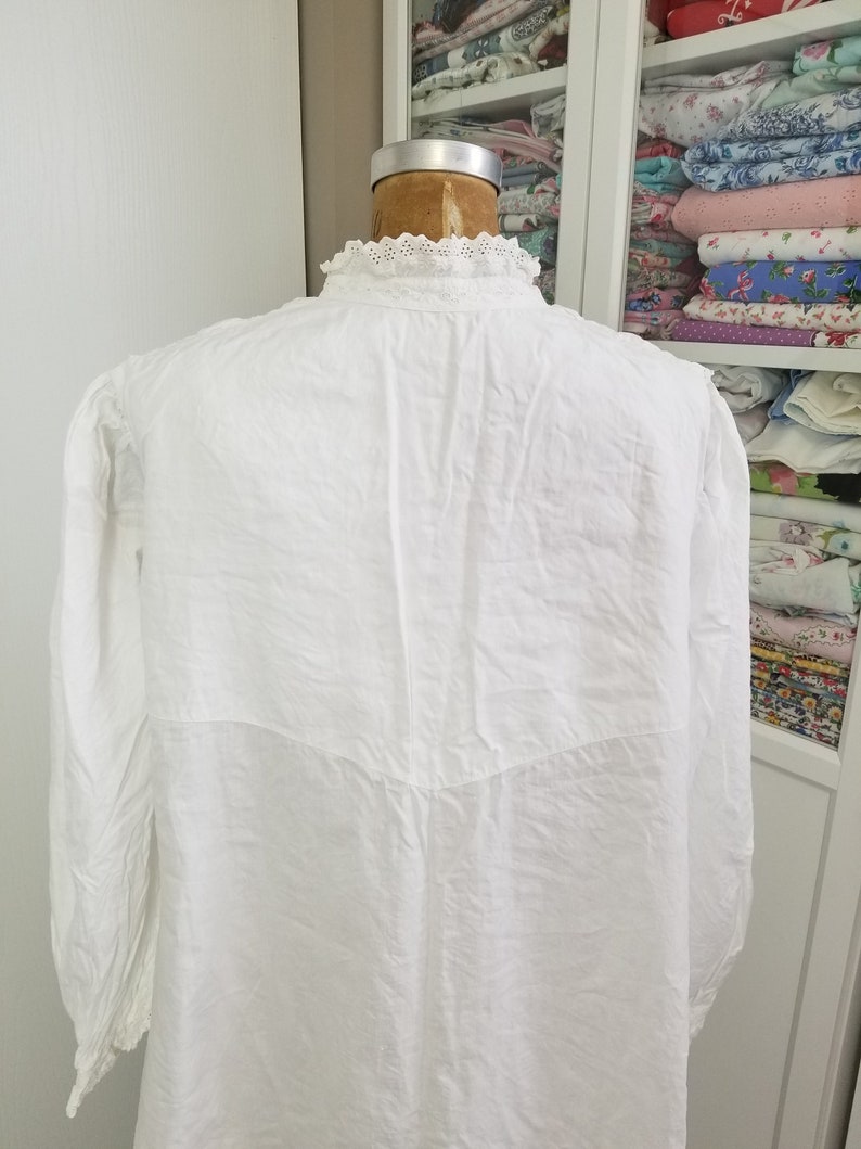 May include: White long-sleeved shirt with a lace collar. The shirt is made from a lightweight fabric and has a relaxed fit.