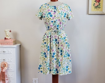 Meibloemen | Vintage jaren 1950/50 blauwe en paarse bloemendagjurk met strikriem | Kay Whitney | Middelgroot tot groot