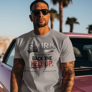 May include: A light gray t-shirt with the text "SMIRK - THE KIND WAY TO SAY BACK THE HELL UP" in black and red. The shirt features a graphic of a knife. The person in the image is wearing sunglasses.