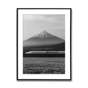 Peut inclure: Tirage encadré en noir et blanc représentant le Mont Fuji, avec son sommet enneigé. Un train à grande vitesse traverse le paysage, avec un champ de fleurs au premier plan. Photographie de paysage.