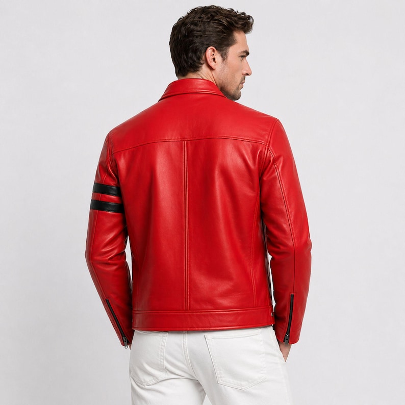 May include: A vibrant red leather jacket featuring black stripes on the left arm. The jacket has a classic collar, zipped pockets, and a fitted design. The model is wearing white trousers. A fashionable outerwear choice.