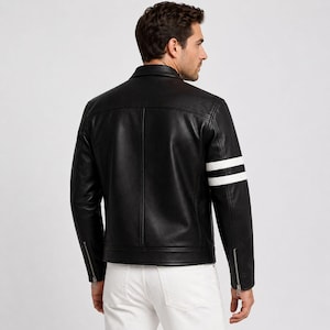 May include: Black leather jacket with white stripes on the sleeves. The jacket features a classic collar, zip details on the sleeves, and a tailored fit. The model is wearing white trousers.