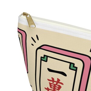Mahjong tile canvas pouch zipper bag — mahjong lover gift featuring a kawaii-style illustrated tile print in pink and cream, shown close up to highlight the gold zipper and bold red Chinese character design.