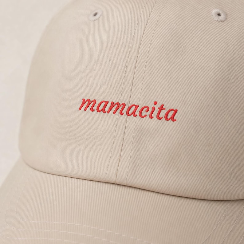 Close up of mamacita red embroidery on beige dad hat showing stitching detail and fabric texture