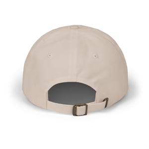 Ask Me About My Audiobook" embroidered dad hat — book lover gift cap shown from the back, displaying a stone beige cotton twill construction with brass slider buckle closure on a clean white background.