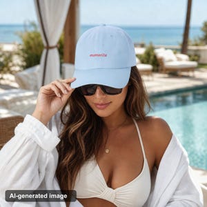 Woman wearing light blue mamacita hat by poolside in vacation setting with sunglasses and swimwear