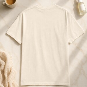 'Eat Sleep Bunco Repeat' bunco dice graphic tee back view flat lay on pale marble — bunco lifestyle gift tee back print detail in a clean editorial wellness scene.