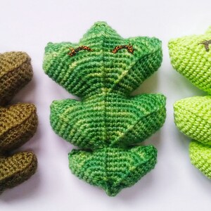May include: Three crocheted leaf-shaped plushies with embroidered eyes. The plushies are green, light green, and brown.