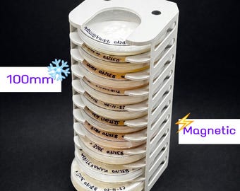 Puede incluir: Un soporte blanco impreso en 3D con múltiples ranuras, diseñado para contener varios recipientes redondos y etiquetados. Los recipientes están apilados verticalmente, y el soporte mide aproximadamente 10 cm de altura. Se muestra la palabra "Magnetic".