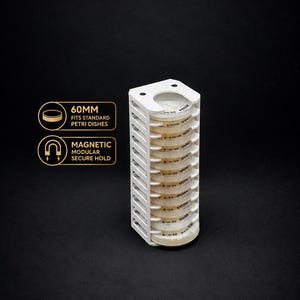 May include: A white vertical rack holding a stack of ten clear petri dishes. The rack features side slots and a top plate. Text on the left indicates 60MM FITS STANDARD PETRI DISHES and MAGNETIC MODULAR SECURE HOLD for the laboratory storage unit.