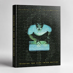 May include: A hardcover book titled "Cracking the Code Third Edition" with a black cover. The cover features a person in a white t-shirt and glasses typing on a keyboard, overlaid on a matrix of numbers.