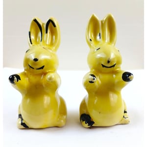 Könnte beinhalten: Ein Set aus drei Keramikbechern mit gesprenkelter, matter Oberfläche. Die Becher sind in Creme-, Hellgrau- und Dunkelgrautönen gehalten. Jeder Becher hat ein schlichtes, modernes Design und einen abgerundeten Griff.