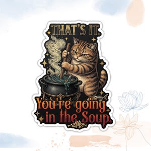 May include: A sticker featuring a tabby cat stirring a cauldron with the text "THAT'S IT. You're going in the Soup." The cat has an angry expression. The cauldron has steam rising from it, and a fish skeleton is visible.