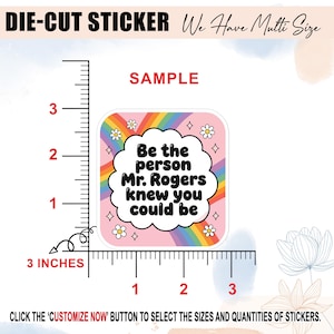 May include: Square die-cut sticker with a pink background, rainbow, and the text "Be the person Mr. Rogers knew you could be." The sticker is 3 inches wide. White flowers and stars surround the text.