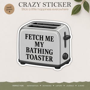 May include: A silver-coloured toaster sticker featuring the black text FETCH ME MY BATHING TOASTER. The illustration depicts a standard two-slot kitchen appliance with a side lever and a circular dial, rendered in a clean, graphic cartoon style.