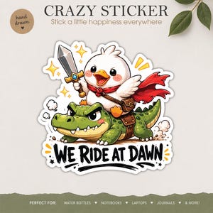 May include: A whimsical sticker featuring a cartoon duck riding a green alligator, holding a sword and wearing a red cape. The sticker has the text "WE RIDE AT DAWN" and is designed for water bottles, notebooks, and laptops.