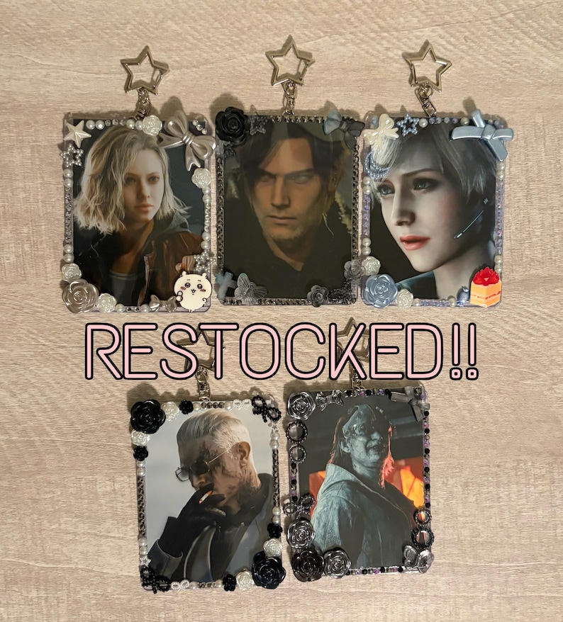 May include: Keychains featuring character portraits, framed with decorative elements like pearls, roses, and bows. The keychains have a star-shaped top and the text "RESTOCKED!!" in pink.