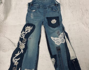 upcycled denim overalls with embroidered appliques' and pearl and lace embellishments.