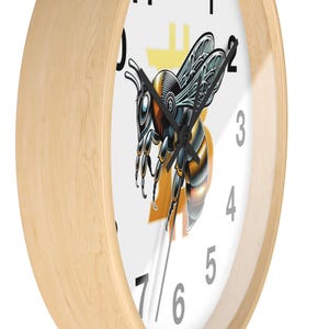 Peut inclure: Une horloge murale ronde avec un cadre en bois clair. Le cadran est blanc avec des chiffres noirs et une illustration détaillée d'une abeille. L'abeille est noire, jaune et orange, avec un symbole Bitcoin jaune.