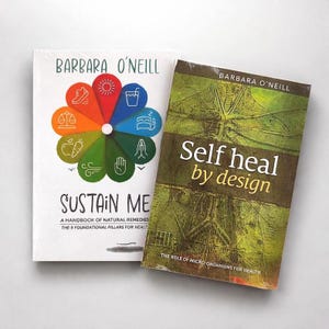 Puede incluir: Dos libros de Barbara O'Neill. El libro de la izquierda se titula "Sustain Me" con un diseño floral colorido. El libro de la derecha se titula "Self heal by design" con una cubierta verde y marrón. Ambos libros están sobre una superficie blanca.