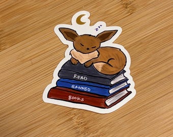 Eevee sleeping on book stack clear sticker - 2 variations - Support Public Libraries & Read Banned Books