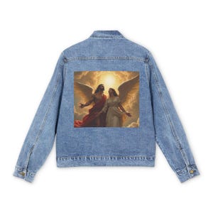 Puede incluir: Chaqueta vaquera azul claro con una pintura colorida de dos ángeles con alas. La obra de arte está centrada en la parte posterior de la chaqueta. La chaqueta tiene un diseño clásico con botones y bolsillos.
