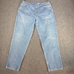 May include: Light blue denim jeans with a classic five-pocket design. The jeans have a straight leg cut and a button and zipper closure. The denim has a faded wash effect, giving them a worn-in look. The jeans are laid flat on a neutral surface.