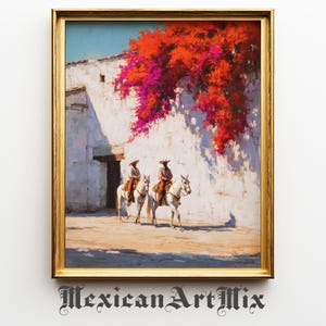 May include: A framed painting depicts two riders on white horses, wearing hats and riding through a sunlit street. A white building with a door and vibrant red and pink flowers is in the background. The painting is in a gold frame.