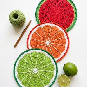 Puede incluir: Posavasos de frutas hechos a mano con ganchillo, con diseños de sandía, naranja y lima. El posavasos de sandía es rojo con detalles verdes y negros. El posavasos de naranja es naranja con detalles blancos. El posavasos de lima es verde con detalles blancos.
