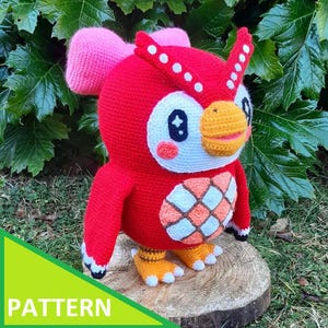 May include: A handmade crochet owl in red, white, pink, orange, and yellow. The owl has large eyes, a beak, and a patterned chest. The word "PATTERN" is in a green triangle in the lower left corner. The owl is sitting on a wooden slice.