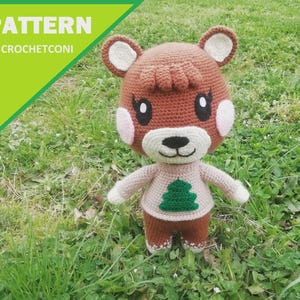 May include: A crocheted deer doll with a brown head, ears, and body, wearing a beige sweater with a green tree design. The doll has white accents on the face and arms. The image includes the text "PATTERN BY CROCHETCONI" in a green and white banner.