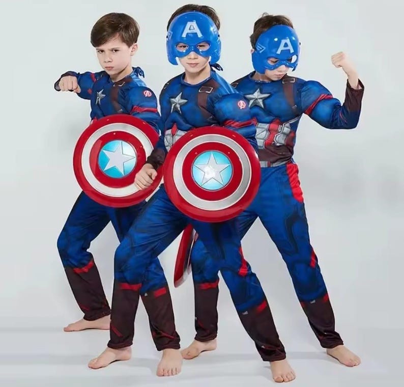 May include: Three children in Captain America costumes, each holding a shield. The costumes are blue with red and white accents, and each child wears a blue mask with a white "A". The shields are red, white, and blue with a star in the center.