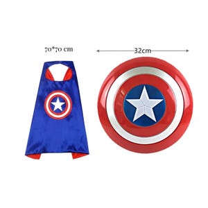 May include: A blue superhero cape with a white star emblem inside a red and white circle, measuring 70 x 70 cm. A red, white, and blue shield with a white star in the center, 32 cm in diameter, is also shown.