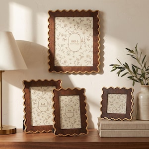 May include: Four dark brown wooden photo frames with scalloped edges and gold trim. The frames contain inserts labeled 8x10, 5x7, 4x6, and 4x4 inches, each featuring a delicate white and brown floral pattern on the background paper.