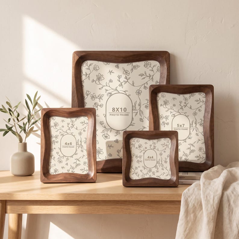 May include: A set of four dark brown wooden photo frames with curved edges, featuring cream-colored inserts with a delicate black floral line drawing pattern. The frames are labeled with sizes 8x10, 5x7, 4x6, and 4x4 inches in oval or rounded rectangular text boxes.